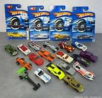 Full lot of 22 Hot Wheels including 4 carded and 18 loose cars shown on tabletop