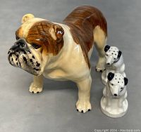 Porcelain British Bulldog figurine and two smaller dog salt and pepper shakers displayed together on grey surface.