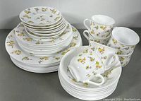 Wide view of the 38-piece set of plates, cups, and saucers with floral pattern on white milk glass.