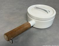 Top angle view of the white enamel lidded pan with wooden handle, closed lid shown.