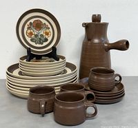 Front angle view of the full set showing all plates stacked, cups with saucers, and the coffee pot with attached lid.