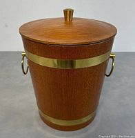 Front view of teak and brass ice bucket with lid on, showing wood grain, brass bands and handles