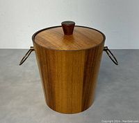 Front view of the teak and brass ice bucket showing lid and brass handles.
