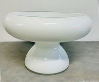 Close-up photo of the white glass pedestal bowl showing its smooth glossy surface and rounded shape.