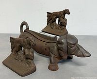 Front angle view showing the dog doorstop and two dog-themed bookends together, highlighting the cast iron material and condition with minor rust.