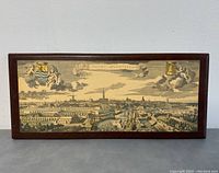 Front view of framed print showing cityscape with ships, buildings, cloudy sky, and two coats of arms in corners.