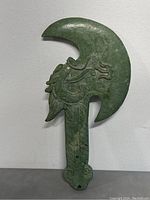 Front view of green stone hand carved dragon axe ornament showing dragon head detail on the axe blade and patterned handle.