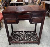 Front view of vanity table with top panels closed, six drawer fronts visible, geometric lattice lower shelf