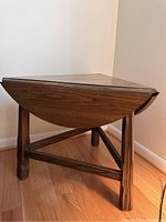 Side view showing three legged base and drop leaf partially extended triangular shape