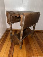 Side view showing turned legs, bottom trough, and one drop leaf raised.