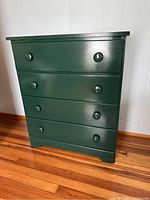 Front view of the green maple dresser showing all four drawers and round knobs.