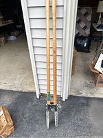 Full view of the post hole digger showing two wooden handles with ruler markings and metal digging blades.