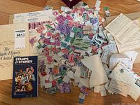 Wide layout showing loose postage stamps in multiple colors, several envelopes containing stamps or correspondence, and two books on philately: 'Stamps & Stories' and 'The Philatelic History of the United States'.