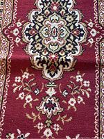 Close-up of central floral medallion on red background showing pattern detail.