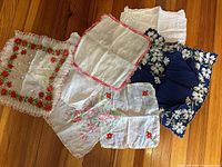 Seven vintage ladies handkerchiefs displayed on wooden surface with visible embroidery and lace edges.