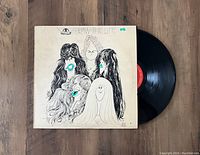 Vinyl record partially pulled from the original album jacket, showing black vinyl and the illustrated cartoon-style band portrait cover with 'DRAW THE LINE' text.