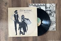 Photo of Fleetwood Mac Rumours vinyl LP with original album cover and partially visible vinyl record and insert.