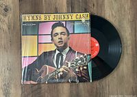 Color photo of vinyl record LP 'Hymns By Johnny Cash' with original jacket visible, showing Johnny Cash on cover holding guitar.