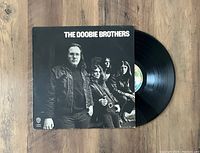 Front view of The Doobie Brothers 1971 vinyl record record LP partially out of black and white album jacket showing band members.
