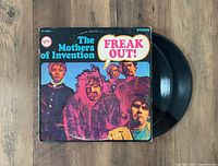 Two vinyl LPs partially pulled out of the original gatefold record jacket showing the front colorful album cover for 'Freak Out!'
