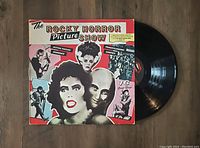 Photo showing the front and part of the vinyl record of The Rocky Horror Picture Show Album with colorful illustrated jacket.