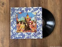 Photo showing The Rolling Stones Their Satanic Majesties Request vinyl record partially out of its colorful album cover on a wooden surface.