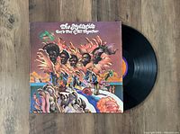 Original colorful album cover with black vinyl record partially out of the jacket, showing label and vinyl grooves.