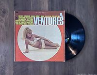 Front cover of The Ventures Golden Greats 1967 vinyl LP showing woman lying down in bikini, orange background with track list.