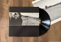 Original jacket front with black and white landscape and band photo, vinyl partially visible to the right, with original insert in the background.