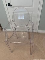 Front view showing the clear plastic desk chair with arms and oval backrest.