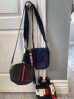 Three crossbody bags hanging on door knob, showing different styles including leather and canvas, with flags detail and Tommy Hilfiger tag visible.