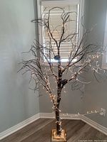 Full view of the artificial decorative tree showing its height and white lights.