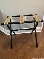 Photo showing luggage rack from an angled front side view, displaying straps and folding legs.