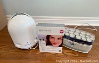 Full lot view showing AirFree air purifier, boxed NuFace facial toning device, and Curlcare hot hair rollers.