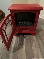 Red Duraflame electric fireplace with door open showing interior logs and controls.