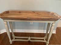 Front view of wooden console table showing tray top with natural wood finish and gray/whitewashed painted base with turned legs.