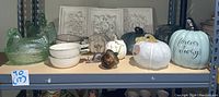 Wide shelf view showing all items together including glass pumpkins, ceramic pumpkins, rooster bakers, resin plaques, metal snail, and glass acorn.