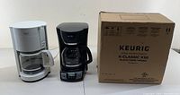 Wide view of Mr.Coffee and KRUPS coffee makers on left and boxed Keurig K-Classic K50 on right