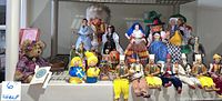 Photo showing a wide assortment of souvenir collectible figures in traditional costumes from different countries arranged on a shelf.