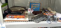 Shelf view showing staplers, punch, haircut kit, King Kong game, and small boxed items.