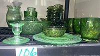 Wide shot showing several green glassware pieces including a large fruit bowl, small bowls, a medium bowl, candle holder and other assorted plates and items
