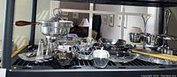 Photo showing the collection of serving pieces including chafing dish, condiment tray, salt and pepper shakers, and various bowls and glass dishes arranged on a shelf.