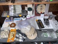 Table covered with a variety of buffing wheels, polishing compounds, polishing cones, diamond hone, and other accessories arranged on a table surface.