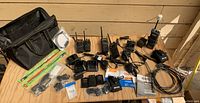 Overview of all items on wood surface including radios, chargers, cables and bag