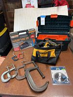 Lot showing DeWalt circular saw in soft carrying bag, Chicago rotary tool kit box, 6 metal clamps in various sizes, and a multicutter blade in packaging.