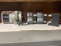 Wide view showing the Delta ShopMaster grinder and three electric belt sanders on a shelf