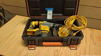 Full view of the open Rigid tool case containing the yellow DeWalt hammer drill and the yellow shop light with orange cord, showing case size and contents.
