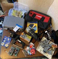 Photo of Dremel kit components including blades, Black and Decker electric tool, Husky tool bag, Irwin blades, and other accessories arranged on a table.