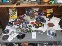 Overview of lot showing Chicago Electric cut off tool on table with multiple discs, wheels, blades, packaging, and accessories scattered around.
