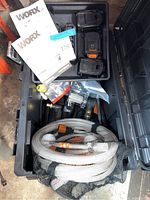 Open HUSKY storage box showing WORX batteries, hoses, and parts of the power cleaner.